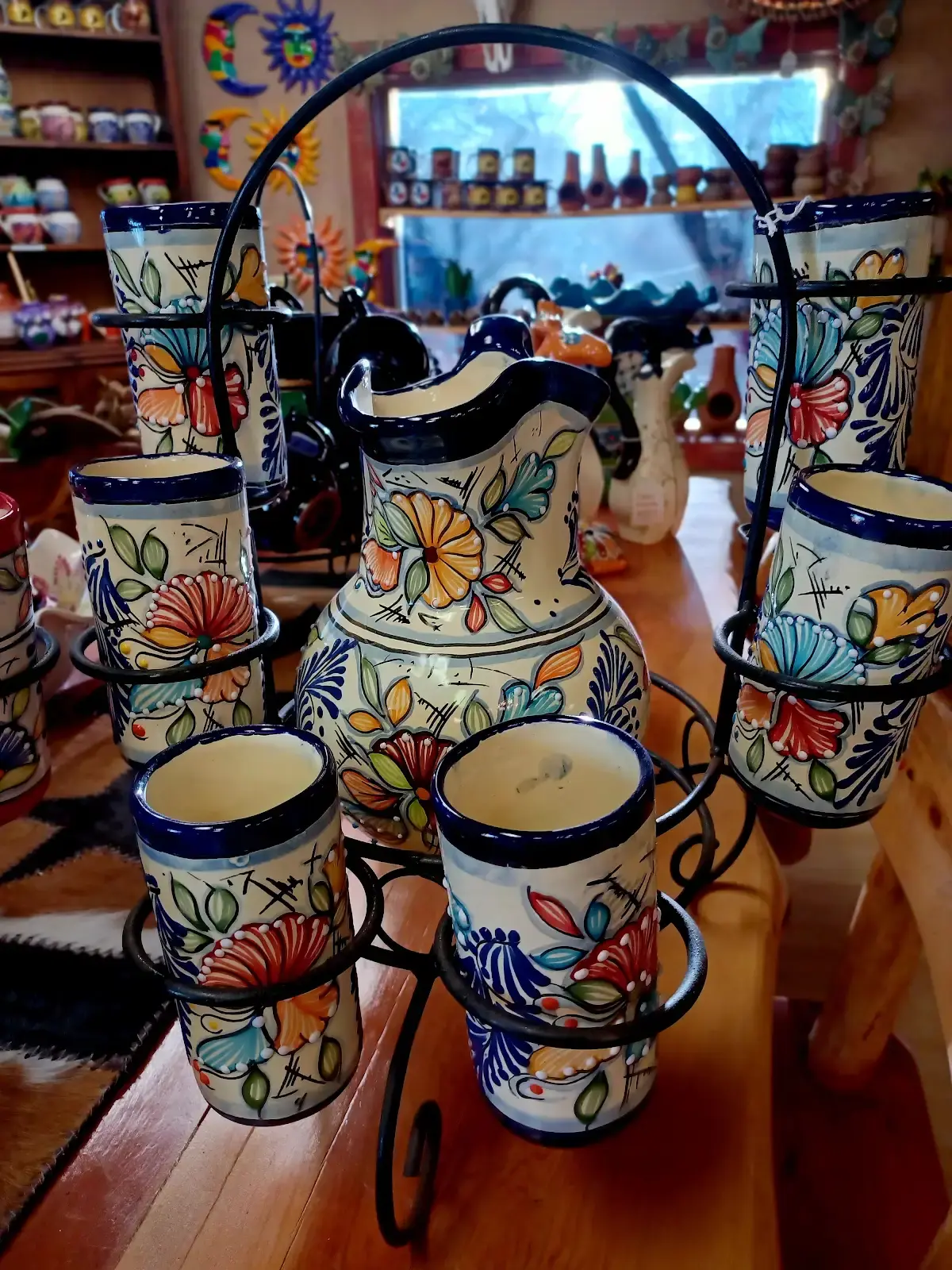 A white teapot with painted, colorful flowers surrounded by matching ups